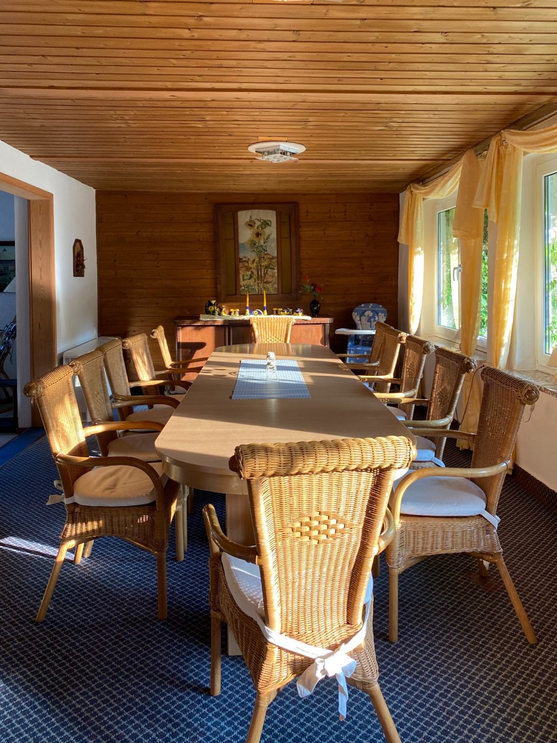Esszimmer Ein heller Raum mit einem langen Tisch und mehreren Stühlen, umgeben von Fenstern.