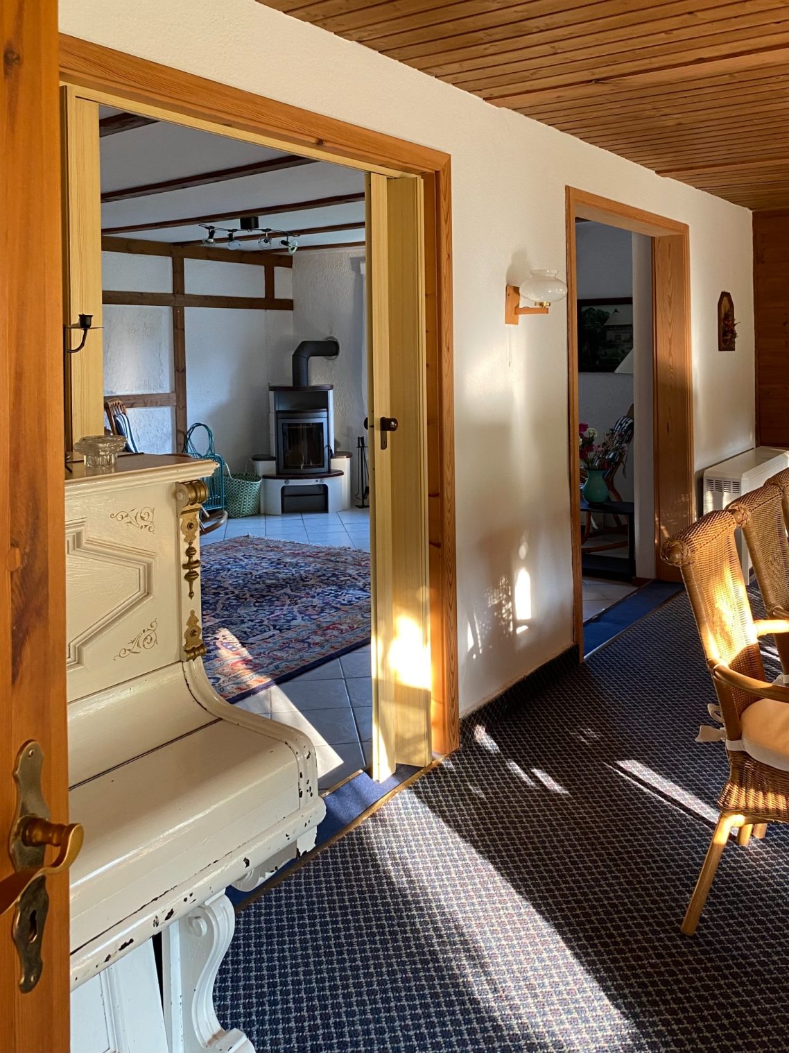 Blick vom Esszimmer ins Kaminzimmer Heller Flur mit sichtbarem Wohnzimmer und einem Klavier in der Ecke.