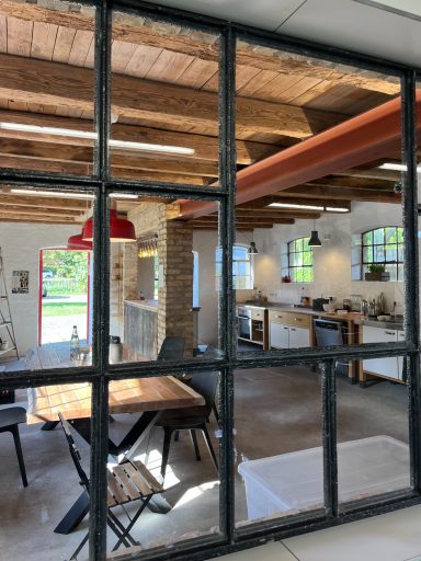 Wartebereich Moderne Küche mit Holzdeckenbalken, Esstisch und großen Fenstern. Helle, offene Atmosphäre.